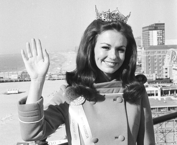 FILE - In this Sept. 13, 1970, file photo, Twenty-one year old Phyllis George of Denton, Texas, waves against backdrop of he beach and ocean at Atlantic City, N.J. a day after she was named Miss America. George, the former Miss America who became a female sportscasting pioneer on CBS's “The NFL Today” and served as the first lady of Kentucky, has died. She was 70. A family spokeswoman said George died Thursday, May 14, 2020, at a Lexington hospital after a long fight with a blood disorder. (AP Photo/Bill Ingraham, File)