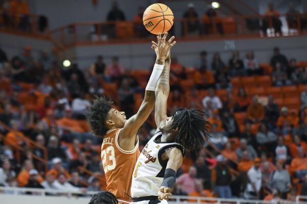 Texas forward Dillon Mitchell (23) and Oklahoma State guard Caleb Asberry (5) reach for a rebound during the first half of an NCAA college basketball game Saturday, Jan. 7, 2023, in Stillwater, Okla. (AP Photo/Brody Schmidt)