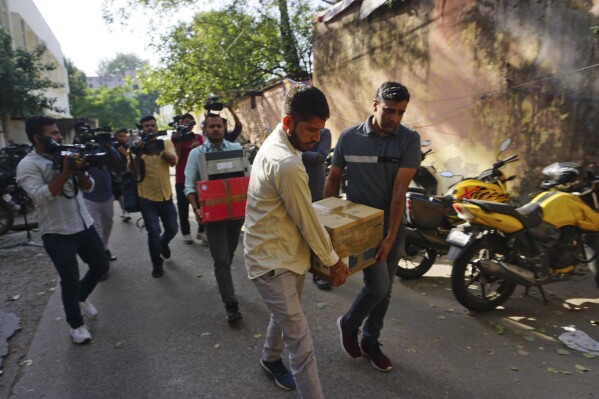 Security officers carry boxes of material confiscated after a raid at the office of NewsClick in New Delhi, India, Tuesday, Oct. 3, 2023. Indian police raided the offices of the news website that's under investigation for allegedly receiving funds from China, as well as the homes of several of its journalists, in what critics described as an attack on one of India's few remaining independent news outlets. (AP Photo/Dinesh Joshi)