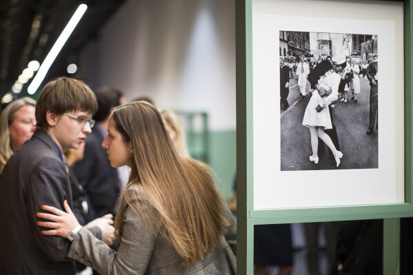 FILE - People speak next to a famous photograph taken by Alfred Eisenstaedt of a sailor kissing a nurse in New York's Times Square on V-J Day at the Jewish Museum and Tolerance Center in Moscow on April 14, 2015. (AP Photo/Alexander Zemlianichenko, File)