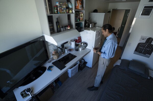 Cheyenne Welbourne stands in his micro-apartment at The Starlight affordable housing building that is run by Central City Concern, a Portland-based homeless services nonprofit, on Friday, March 15, 2024, in Portland, Ore. Welbourne moved into one of the nonprofit's single room occupancy units in downtown Portland last March after years of living on the streets. (AP Photo/Jenny Kane)