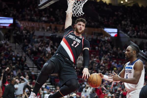 FILE - Portland Trail Blazers center Jusuf Nurkic, left, hangs on the rim after dunking in front of to Minnesota Timberwolves guard Jaylen Nowell during the first half of an NBA basketball game in Portland, Ore., Tuesday, Jan. 25, 2022. Nurkic agreed to a $70 million contract with Portland, Friday, July 1, 2022. (AP Photo/Craig Mitchelldyer, File)