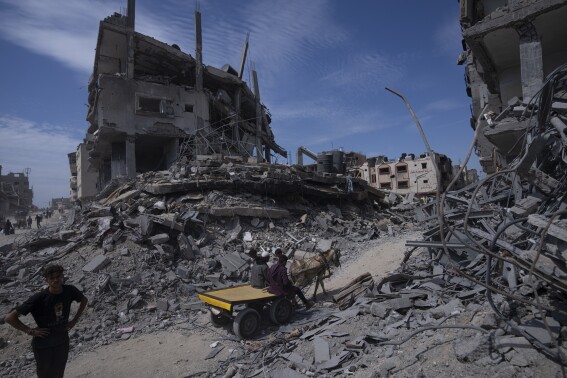 Palestinos caminan entre la destrucción tras una ofensiva aérea y terrestre israelí en Jan Yunis, sur de la Franja de Gaza, el lunes 8 de abril de 2024. (AP Foto/Fatima Shbair)