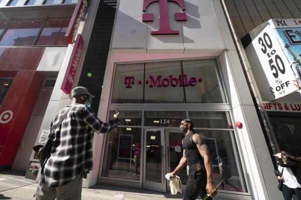 A man uses a mobile phone outside a T-Mobile store, Monday, April 19, 2021,  in New York. The wireless carrier agreed to pay $19.5 million in a settlement with the Federal Communications Commission over a 12-hour nationwide outage in June 2020 that resulted in thousands of failed 911 calls. The FCC said Tuesday, Nov. 23 that as part of the settlement, T-Mobile will also commit to improving communications of outages to emergency call centers, among other measures. (AP Photo/Mark Lennihan)