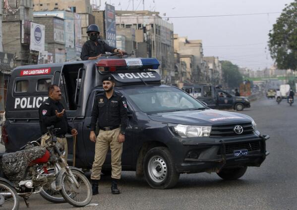 Police officers stand guard at a deserted road due to strikes called by the the country's religious political parties over the security forces's crackdown against a banned Tehreek-e-Labaik Pakistan party, in Karachi, Pakistan, Monday, April 19, 2021. An outlawed Pakistani Islamist political group freed 11 policemen almost a day after taking them hostage in the eastern city of Lahore amid violent clashes with security forces, the country's interior minister said Monday. (AP Photo/Fareed Khan)