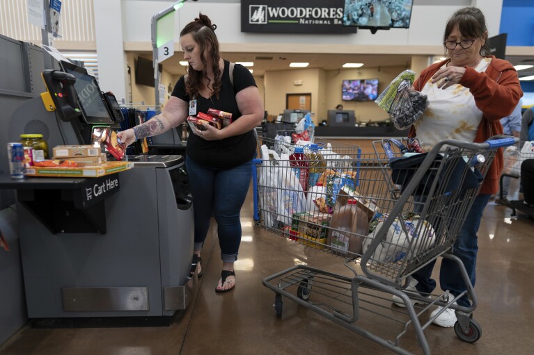 Jesse Johnson, left, of the Family Resource Center helps her client Jodi Ferdinandsen check out at Walmart in Findlay, Ohio, Thursday, Oct. 12, 2023. (AP Photo/Carolyn Kaster)