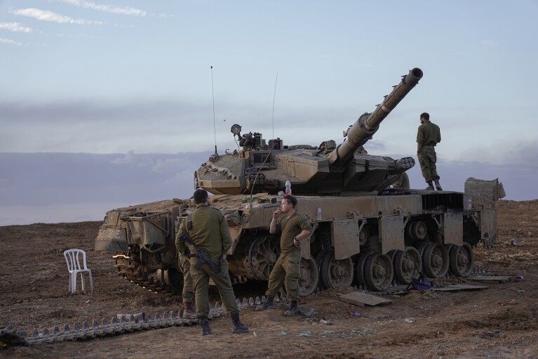 Israeli soldiers work on a tank near the border with the Gaza Strip, southern Israel, Tuesday, Nov. 28, 2023.  On the fifth day of the temporary ceasefire between Israel and Hamas.  (AP Photo/Ohad Zweigenberg)