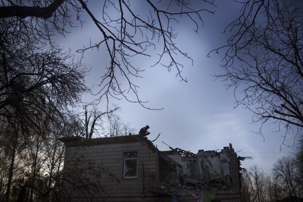 A Ukrainian serviceman stands atop a damaged kindergarten following a Russian drone attack in Kyiv, Ukraine, Saturday, Nov. 25, 2023. Russia launched its most intense drone attack on Ukraine since the beginning of its full-scale invasion on Saturday morning, military officials said. (AP Photo/Felipe Dana)