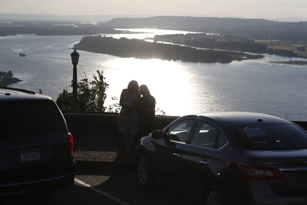 In this July 22, 2019, photograph, a couple look over the Columbia River as the suns sets from the Vista House at Crown Point State Park near Corbett, Or. People are headed out into the great outdoors as the new coronavirus has made for turbulent times. The new coronavirus causes mild or moderate symptoms for most people, but for some, especially older adults and people with exisitng health problems, it can cause more severe illness or death. (AP Photo/David Zalubowski)