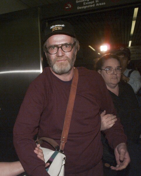FILE — James Lewis is escorted through Boston's Logan Airport, Friday Oct. 13, 1995, after being released from the Federal Correctional Institution in Oklahoma. Lewis, the suspect in the 1982 Tylenol murders, was found dead Sunday, July 9, 2023 at his home in Cambridge, Mass., law-enforcement sources said. (AP Photo/Charles Krupa, File)
