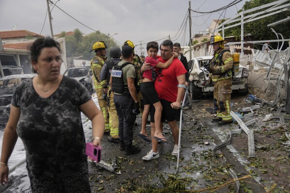 Israelis evacuate a site struck by a rocket fired from the Gaza Strip in Ashkelon, southern Israel, Monday, Oct. 9, 2023. (AP Photo/Ohad Zwigenberg)