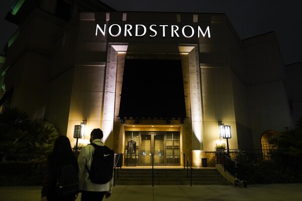 FILE - Two pedestrians walk near an entrance to a Nordstrom department store at the Grove mall in Los Angeles, Dec. 2, 2021. Bruce Nordstrom, a retail executive who helped expand his family’s Pacific Northwest department store chain into an upscale national brand, has died. Seattle-based Nordstrom Inc. said its former chairman died at his home, Saturday, May 18, 2024. He was 90. (AP Photo/Jae C. Hong, File)
