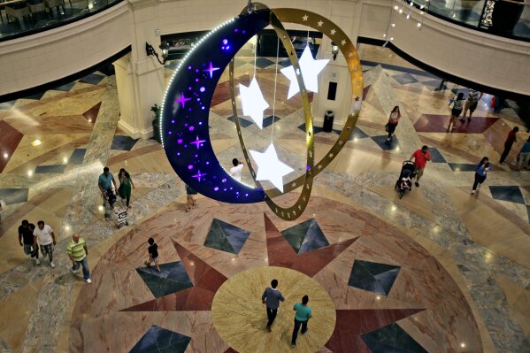 FILE - In this Saturday, June 28, 2014, file photo, people walk inside a shopping mall with Ramadan decorations as they prepare for the holy month of Ramadan in Dubai, United Arab Emirates. As the holy Muslim fasting month of Ramadan approached, Dubai is parting with a longstanding requirement that restaurants must be covered by curtains during sunlight hours. (AP Photo/Kamran Jebreili, File)