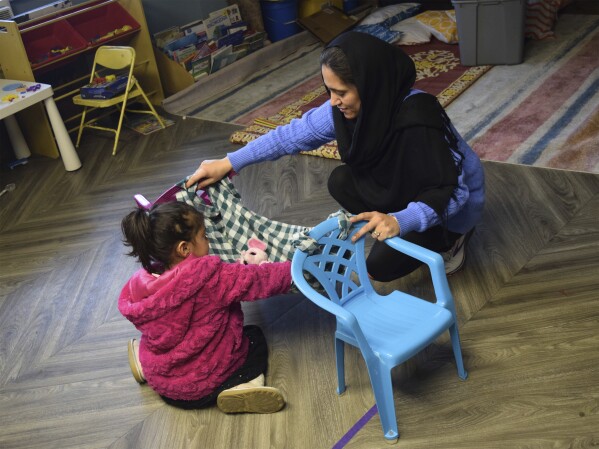 Home visitor Fatema Zamani and her 4-year-old daughter Kaenat build a homemade hammock, imitating a scene from a children's book they just read on April 3, 2024, in Denver, Colo. Zamani will introduce the book and the activity to families in her caseload, most of whom recently relocated to the United States from Afghanistan. (Emily Tate Sullivan/EdSurge via AP)