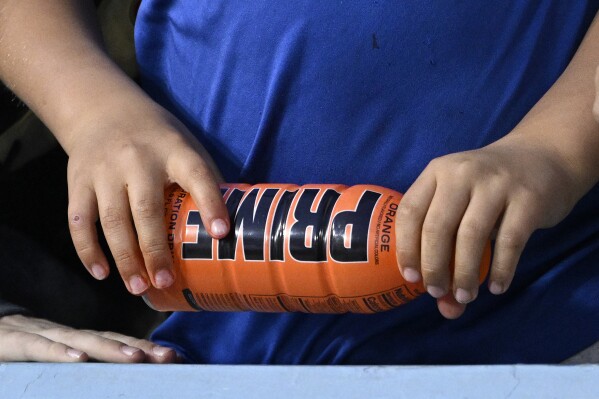 FILE - A child holds a PRIME Hydration drink, which contains no caffeine, prior to a baseball game between the Los Angeles Dodgers and the Arizona Diamondbacks, March 31, 2023, in Los Angeles. PRIME also makes a highly caffeinated energy drink that has earned viral popularity among children and is facing scrutiny from federal lawmakers and health experts. On Sunday, July 9, 2023, Sen. Chuck Schumer called on the Food and Drug Administration to investigate PRIME. (AP Photo/Mark J. Terrill, File)
