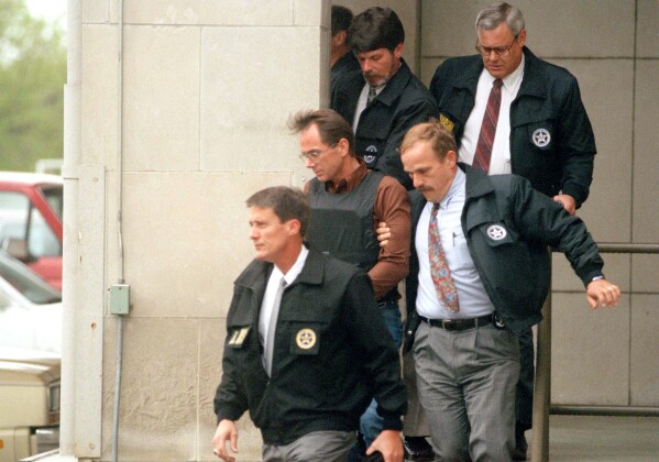 Terry Nichols, wearing a bullet-proof vest, is escorted by U.S. marshals as he leaves the federal courthouse in Wichita, Kansas, on April 26, 1995. (AP Photo/Steve Rasmussen, File)