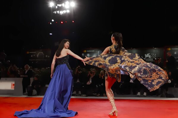 File - Actresses Qi Wei, left, and Tao Okamoto pose for photographers at the premiere for the film "Zhuibu" (Manhunt) at the Venice Film Festival. The 77th Venice Film Festival will kick off on Wednesday, Sept. 2, 2020, but this year's edition will be unlike any others. Coronavirus restrictions will mean fewer Hollywood stars, no crowds interacting with actors and other virus safeguards will be deployed. (AP Photo/Domenico Stinellis, File)