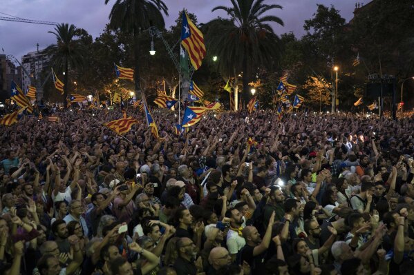 
              Pro-independence supporters club hands during a rally as they watch Catalan President Carles Puigdemont speaking in parliament, on a giant screen in Barcelona, Spain, Tuesday, Oct. 10, 2017. Puigdemont said the region remained committed to independence but said it should follow dialogue with the government in Madrid. (AP Photo/Felipe Dana)
            