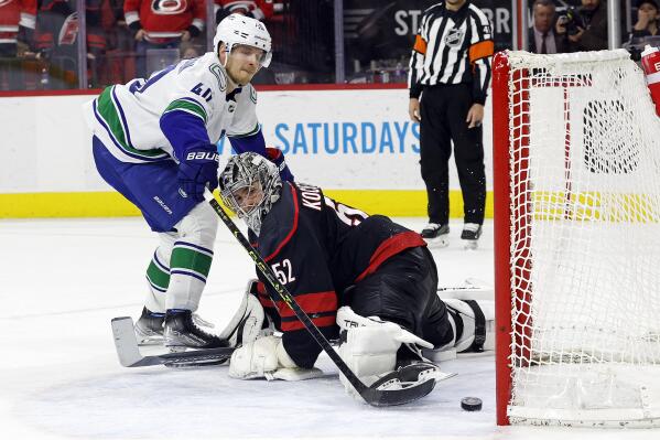 Vancouver Canucks' Elias Pettersson (40) slips the puck past Carolina Hurricanes goaltender Pyotr Kochetkov (52) to win the game in a shoot out at an NHL hockey game in Raleigh, N.C., Sunday, Jan. 15, 2023. (AP Photo/Karl B DeBlaker)