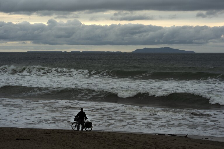 Long distance expedition cyclist Stu LaBrosse takes self videos overlooking the Channel Islands archipelago ahead of storms in Ventura, Calif., Wednesday, Jan. 31, 2024. (AP Photo/Damian Dovarganes)