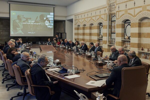 In this photo, released by the Lebanese Presidency press office, Lebanese president Joseph Aoun, center foreground, and Lebanese Prime Minister Nawaf Salam, right, head a cabinet meeting at the presidential palace in Baabda, east of Beirut, Lebanon, Thursday, April 17, 2025. The Arabic on the screen reads, "Summary of the situation and security measures taken." (Lebanese Presidency press office via AP)