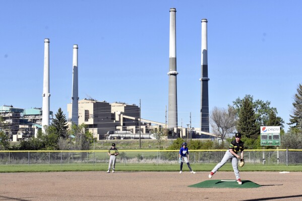 The coal-fired Colstrip Generating Station is seen behind youths playing baseball on Tuesday, May 28, 2024, in Colstrip, Mont. Republicans and some Democrats are pushing back against the Biden administration's plans to curb coal pollution and end new mining leases for the fuel in the Powder River Basin of Montana and Wyoming. (AP Photo/Matthew Brown)