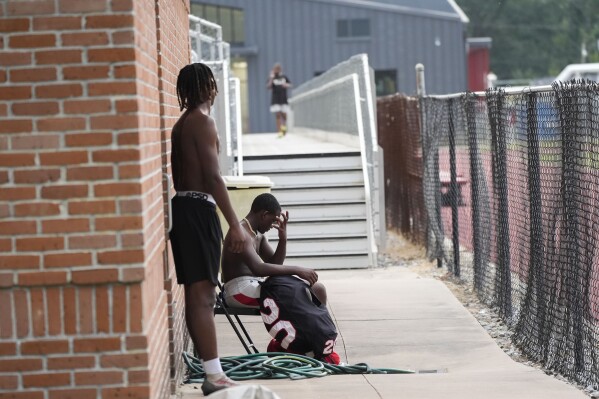 Members of the Baker High football team wait out a weather delay at practice in Baker, La., Wednesday, Aug. 28, 2024. (AP Photo/Gerald Herbert)