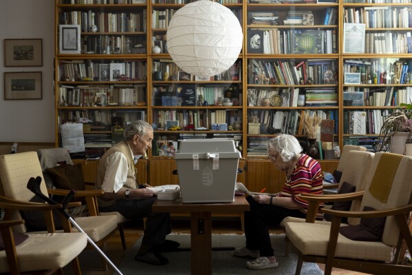 An elderly couple vote at their home using a mobile ballot box during the European Parliamentary elections, in Budapest, Hungary, Sunday, June 9, 2024. (AP Photo/Denes Erdos)