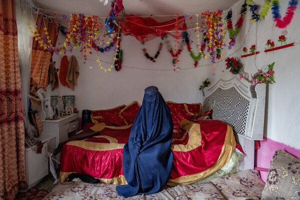 Fahimeh, 14, from an internally displaced family, sits on the bed in the room where she got married, on the outskirts of Kabul, Afghanistan, Tuesday, May 23, 2023. (AP Photo/Ebrahim Noroozi)