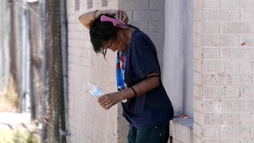 A person tries to cool off in the shade as temperatures are expected to hit 116-degrees Fahrenheit, Tuesday, July 18, 2023, in Phoenix. The extreme heat scorching Phoenix set a record Tuesday, the 19th consecutive day temperatures hit at least 110 degrees Fahrenheit. (AP Photo/Ross D. Franklin)