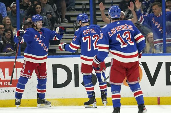New York Rangers defenseman Jacob Trouba, left, celebrates with teammates, including center Filip Chytil, center, and left wing Alexis Lafrenière, right, after scoring against the Tampa Bay Lightning during the second period of an NHL hockey game Saturday, March 19, 2022, in Tampa, Fla. (AP Photo/Chris O'Meara)