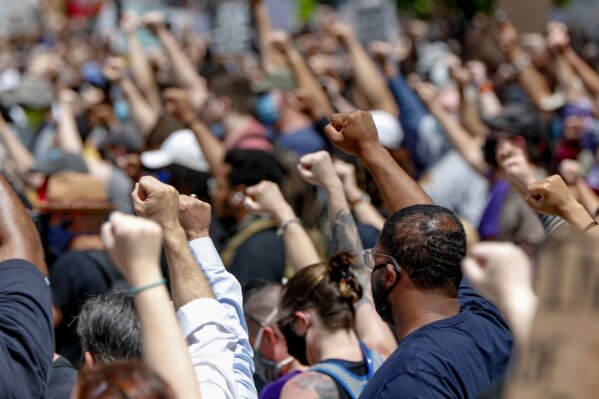 FILE - In this Saturday, May 30, 2020, file photo, demonstrators raise fists in the air during a march in Pittsburgh to protest the death of George Floyd, who died after being restrained by Minneapolis police officers on May 25. A black reporter from the Pittsburgh Post-Gazette was pulled from covering the city’s protests over the death of George Floyd, apparently because of a tweet. (AP Photo/Keith Srakocic, File)