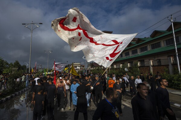 A man waves a flag that reads "O! Hussein" as Kashmiri Shiite Muslims participate in a Muharram procession in Srinagar, Indian controlled Kashmir, Thursday, July 27, 2023. Muharram is a month of mourning for Shiite Muslims in remembrance of the martyrdom of Imam Hussein, the grandson of the Prophet Muhammad. (AP Photo/Dar Yasin)