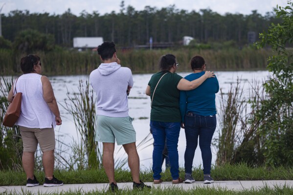 People gather at the scene where five teenagers were found dead in a submerged vehicle in a retention pond in Fort Myers, Fla., Monday, June 26, 2023. Authorities say an out-of-control car landed in a southwest Florida retention pond where it went underwater, killing all five teenagers in the vehicle. (Andrew West/The News-Press via AP)