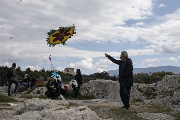 A man flies a kite as in the background stands the ancient Parthenon temple in Athens, on Clean Monday, March 15, 2021. The coronavirus pandemic, which hit Greece especially hard this winter, threatened to ground the kite-flying, an essential part of the celebration of Clean Monday, the first day of Lent. (AP Photo/Petros Giannakouris)