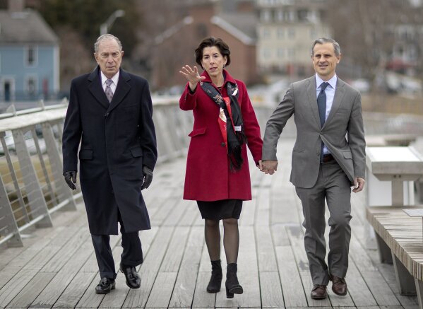 FILE - In this Feb. 5, 2020, file photo,Democratic presidential candidate and former New York City Mayor Michael Bloomberg, left, walks with Rhode Island Gov. Gina Raimondo, center, and her husband, Andrew Moffit, over a recently opened pedestrian bridge to a campaign event for Bloomberg, in Providence, R.I. Raimondo and the state Democratic Party have received thousands of dollars from Bloomberg and his daughter, and groups he gave millions to in 2014 spent more than $1 million to help her win the governor's seat. (AP Photo/David Goldman)