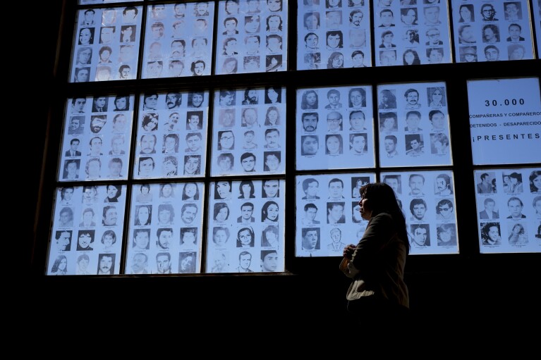 Claudia Poblete poses for a photo in front of a display of photographs of people disappeared during Argentina's military dictatorship at the Museum of Space for Memory and the Promotion and Defense of Human Rights, in Buenos Aires, Argentina, Friday, March 22, 2024. Poblete is one of the 133 “recovered grandchildren” of Argentina. (AP Photo/Natacha Pisarenko)