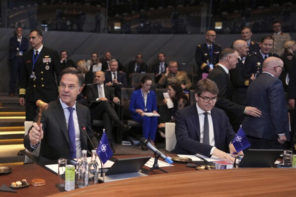 NATO Secretary General Mark Rutte, left, bangs a gavel to signify the start of a meeting of NATO defense ministers at NATO headquarters in Brussels, Thursday, June 5, 2025. (AP Photo/Virginia Mayo)