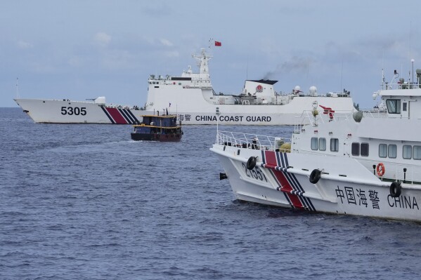 Ένα πλοίο ανεφοδιασμού των Φιλιππίνων, στο κέντρο, κάνει ελιγμούς γύρω από σκάφη της κινεζικής ακτοφυλακής καθώς προσπαθούν να εμποδίσουν το δρόμο τους κοντά στο Second Thomas Shoal, γνωστό τοπικά ως Ayungin Shoal, στην αμφισβητούμενη Θάλασσα της Νότιας Κίνας την Τρίτη, 22 Αυγούστου 2023. Ως μέλος του Αμερικανικό Ναυτικό, ένα αεροπλάνο πέταξε από πάνω, δύο σκάφη του Πολεμικού Ναυτικού των Φιλιππίνων παραβίασαν τον αποκλεισμό της κινεζικής ακτοφυλακής σε μια επικίνδυνη αντιπαράθεση στη διαφιλονικούμενη Θάλασσα της Νότιας Κίνας, παραδίδοντας με επιτυχία τρόφιμα και άλλες προμήθειες στις δυνάμεις των Φιλιππίνων που περιπολούν τα αμφισβητούμενα κοπάδια στο BRP Sierra Madre.  (AP Photo/Aaron Favela)