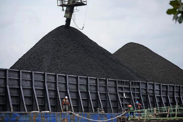 Workers check the rope on a barge as it's being loaded with coal in Kutai Kartanegara, East Kalimantan, Indonesia, Tuesday, Dec. 20, 2022. Indonesia, one of the world's largest coal-producing countries, has agreed to drastically reduce its reliance on fossil fuels in the coming decades. (AP Photo/Dita Alangkara)