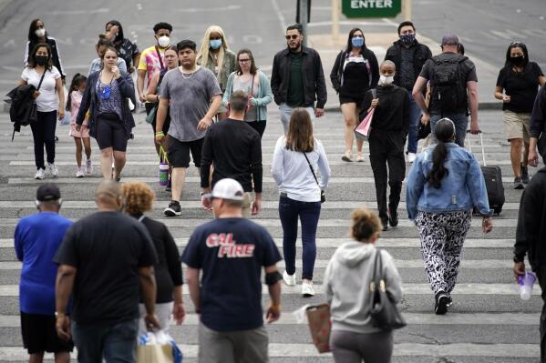 Masked and unmasked pedestrians walk along the Las Vegas Strip, Tuesday, April 27, 2021, in Las Vegas. The Centers for Disease Control and Prevention eased its guidelines Tuesday on the wearing of masks outdoors, saying fully vaccinated Americans don't need to cover their faces anymore unless they are in a big crowd of strangers. (AP Photo/John Locher)