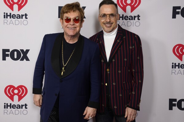 FILE - Icon award winner Elton John, left, and David Furnish attend the iHeartRadio Music Awards at the Dolby Theatre, May 27, 2021, in Los Angeles. Photos of iconic celebrities and historic moments from the collection of Elton John and David Furnish will go on display at London’s Victoria and Albert Museum next year. The museum said Tuesday Oct. 24, 2023, that the exhibition, titled “Fragile Beauty,” will include 300 images by more than 140 photographers, including Diane Arbus, Cindy Sherman, Robert Mapplethorpe, William Eggleston, Zanele Muholi and Ai Weiwei. (AP Photo/Chris Pizzello, File)