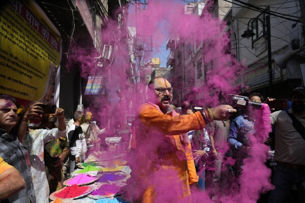 A Hindu man sprays coloured powder as people celebrate Holi, the Hindu festival of colors, in Jammu, India, Monday, March. 25, 2024. (AP Photo/Channi Anand)