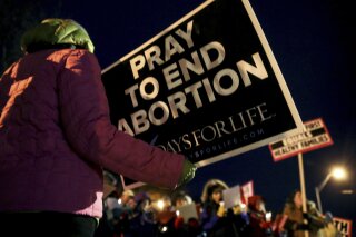 
              FILE - In this Dec. 12, 2016, file photo, protesters hold anti-abortion signs outside the Planned Parenthood Columbia Health Center on in Columbia, Mo. Planned Parenthood Great Plains spokeswoman Emily Miller says abortions scheduled for Wednesday, Oct. 3, 2018, at the Columbia clinic are canceled. Federal appeals judges ruled last month that Missouri can enforce a requirement that doctors performing abortions must have admitting privileges at hospitals. The Columbia clinic hasn't met that requirement. (Timothy Tai/Columbia Daily Tribune via AP, File)
            
