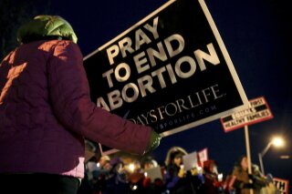 FILE - In this Dec. 12, 2016, file photo, protesters hold anti-abortion signs outside the Planned Parenthood Columbia Health Center on in Columbia, Mo. Planned Parenthood Great Plains spokeswoman Emily Miller says abortions scheduled for Wednesday, Oct. 3, 2018, at the Columbia clinic are canceled. Federal appeals judges ruled last month that Missouri can enforce a requirement that doctors performing abortions must have admitting privileges at hospitals. The Columbia clinic hasn't met that requirement. (Timothy Tai/Columbia Daily Tribune via AP, File)