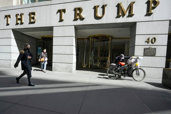 FILE - Pedestrians and a food delivery man are seen outside the Trump building on Wall Street, in New York's Financial District, March 23, 2021. (AP Photo/Mary Altaffer, File )