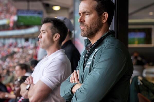 This image released by FX shows Rob McElhenney, left, and Ryan Reynolds in a scene from the docuseries "Welcome to Wrexham," which follows them as they takeover the lower-league Welsh soccer team Wrexham AFC. (Patrick McElhenney/FX via AP)