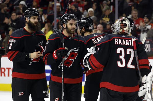Carolina Hurricanes goaltender Antti Raanta (32) is congratulated by Jordan Martinook, center, and Brent Burns (8) after the team's win over the Philadelphia Flyers in an NHL hockey game in Raleigh, N.C., Friday, Dec. 23, 2022. (AP Photo/Karl B DeBlaker)
