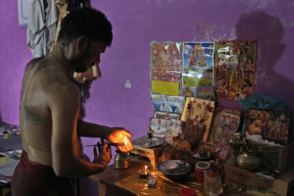 Sunil Kumar Naik, an ambulance driver, prays after taking a bath as he gets ready for the day, in Banpur in the Indian state of Uttar Pradesh, Sunday, June 18, 2023. Ambulance drivers and other healthcare workers in rural India are the first line of care for those affected by extreme heat. (AP Photo/Rajesh Kumar Singh)