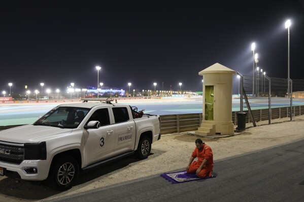 A race marshal prays next to the course during the qualifying session ahead of the Formula One Bahrain Grand Prix at the Bahrain International Circuit in Sakhir, Bahrain, Saturday, April 12, 2025. (AP Photo/Altaf Qadri)